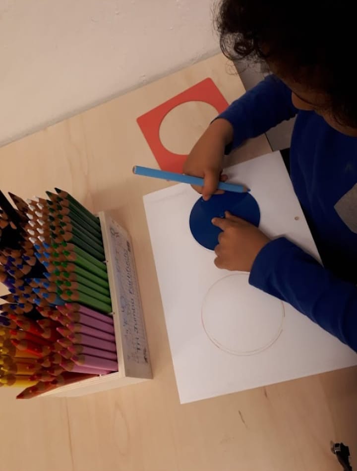 Ein Kind fährt mit dem Stift an einer runden Schablone entlang