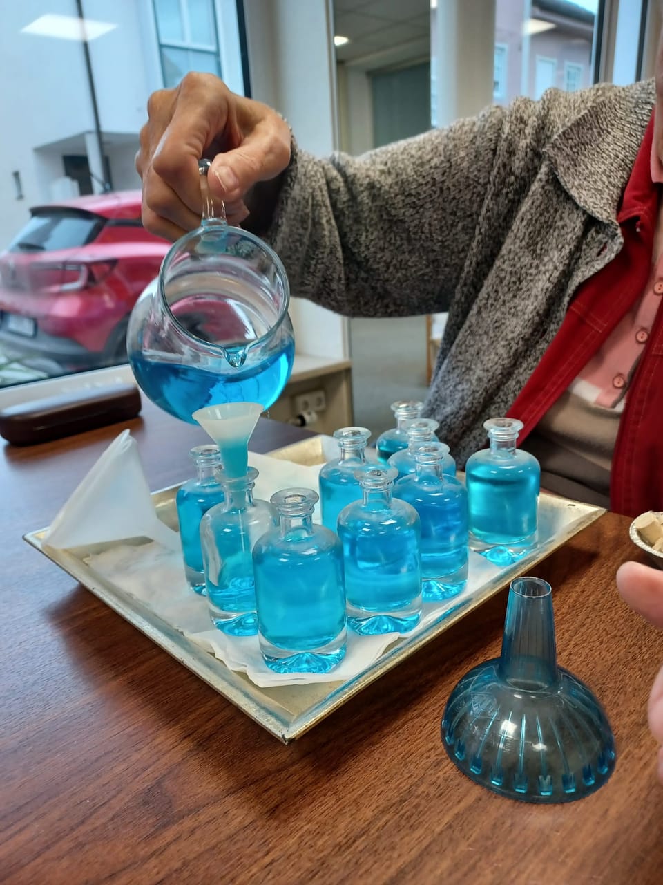 Blau gefärbtes Wasser wird in kleine Glasflaschen umgegossen