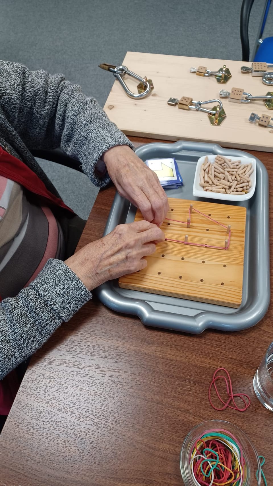 Hände spannen Gummibänder über ein Nagelbrett